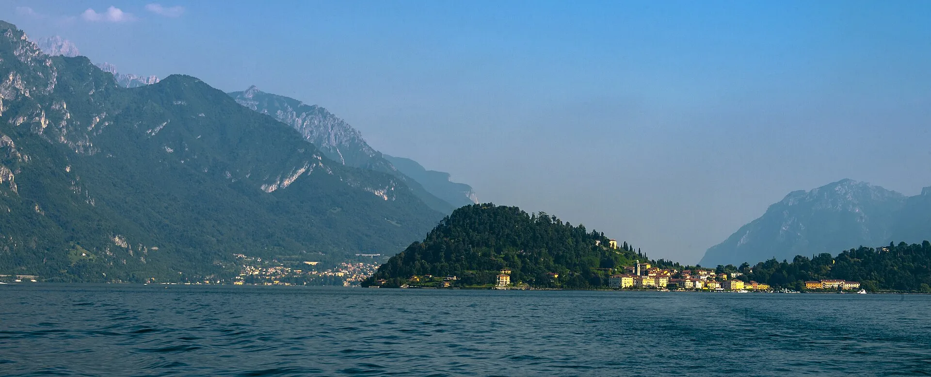 Ferry naviguant sur un lac italien devant un village au pied des montagnes